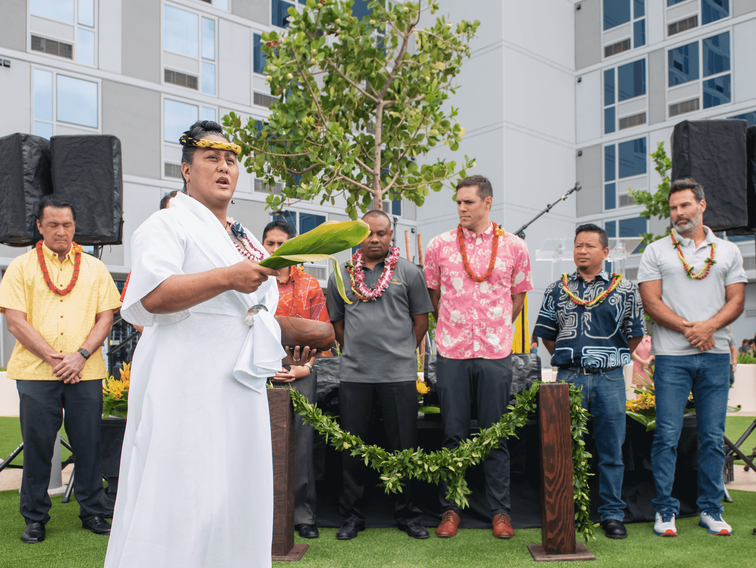 Seven people stand side-by-side in reverence during the blessing at Ke Kilohana