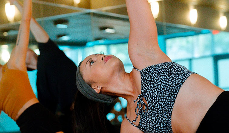 Woman in a group holding a chest opening yoga pose