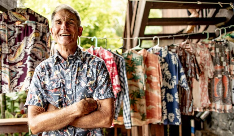 Dale Hope stands in front of his vintage aloha shirt collection