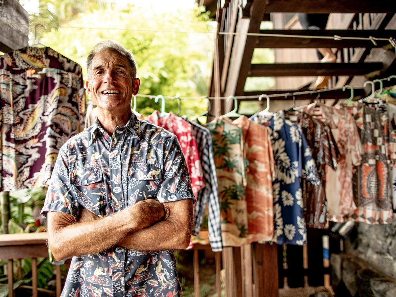 Dale Hope stands in front of his vintage aloha shirt collection