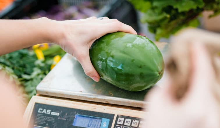 Green vegetable being weighed on a scale at Kakaako Farmers Market