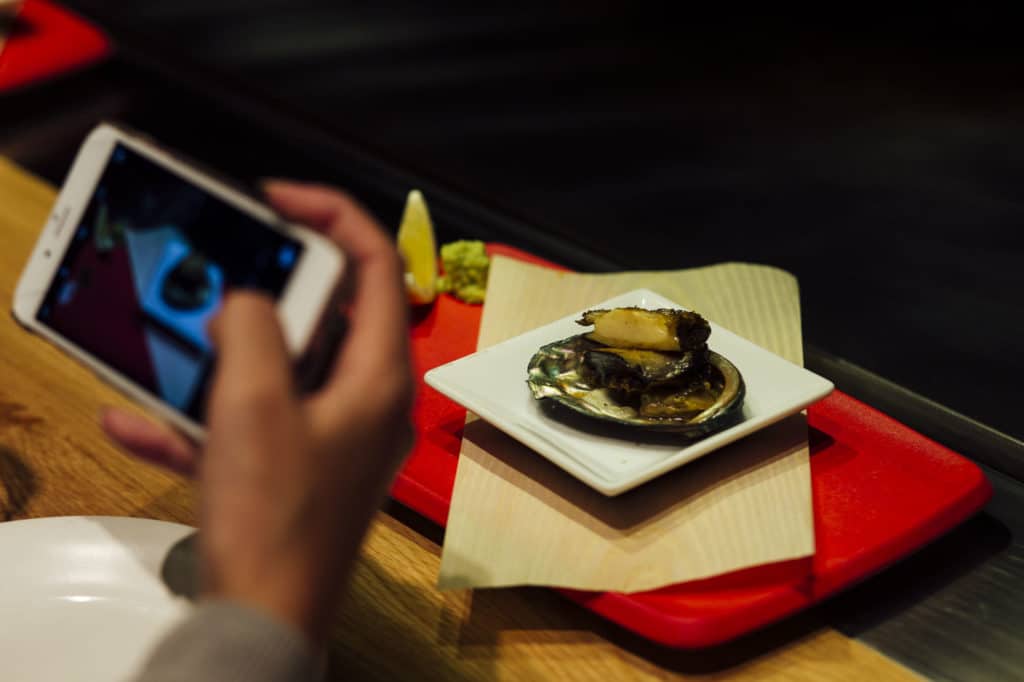 Person taking a mobile phone photograph of a meal