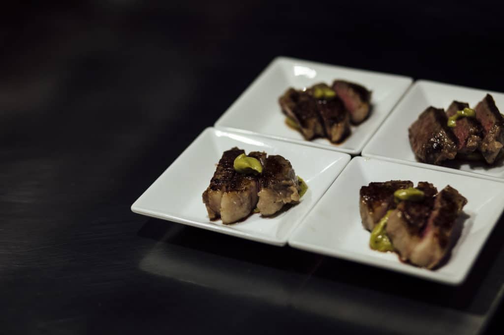 Four plated dishes of meat