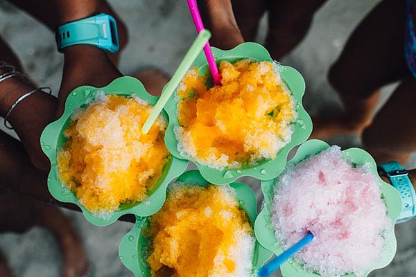 Four colorful cups of shave ice with straws