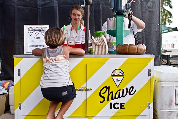 Young child sits close to a shave ice truck waiting to be served