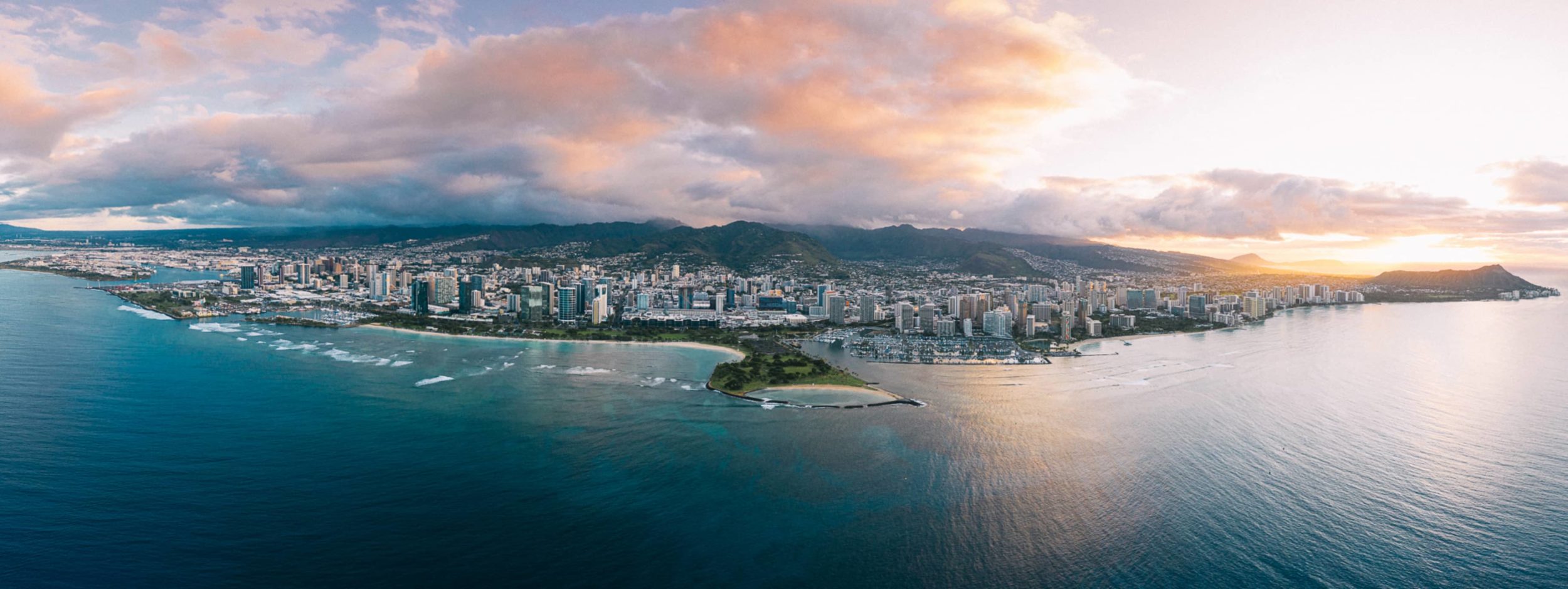 Aerial photo of Honolulu with ocean, mountains, and buildings