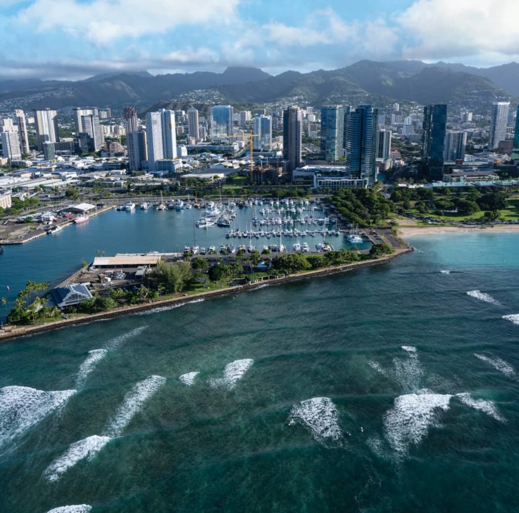 Aerial photo of a Honolulu harbor, ocean, mountain, and buildings