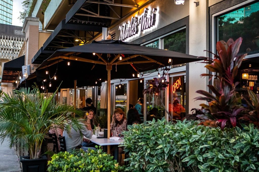 Group of friends enjoying outdoor, open-air dining in front of Maile's Thai