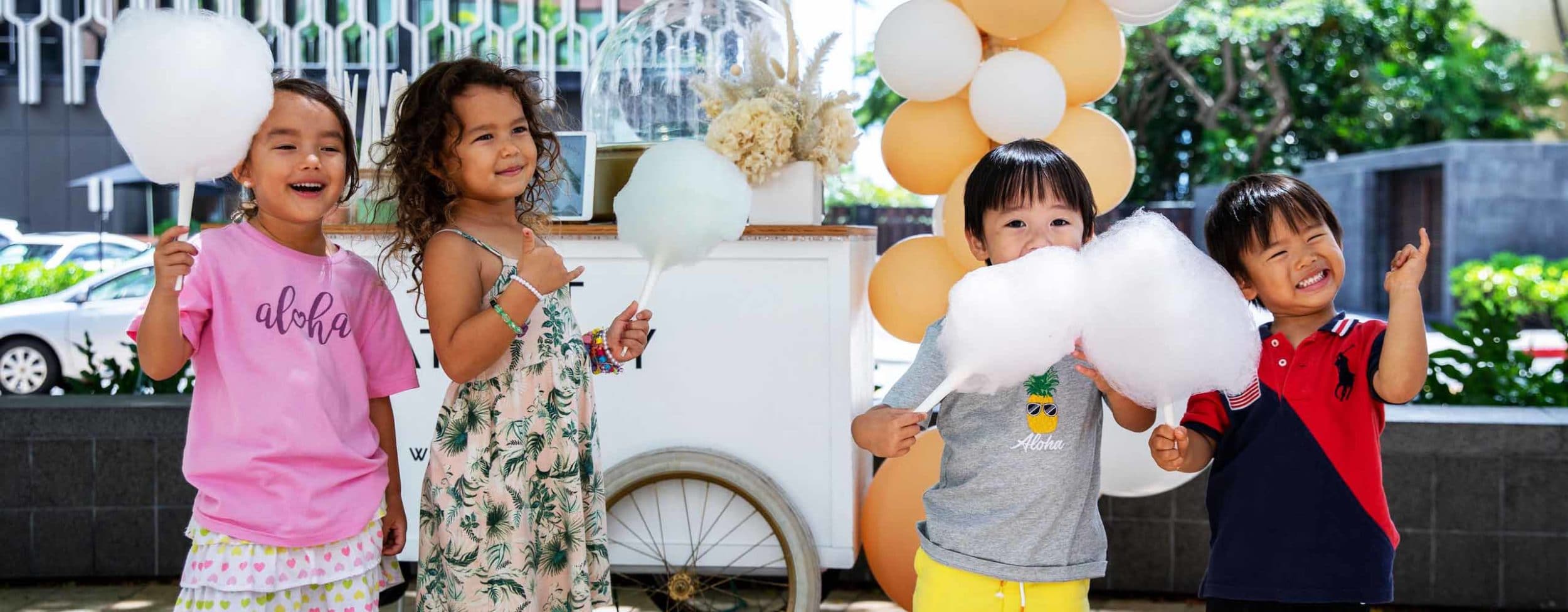 Four children standing while smiling and eating cotton candy