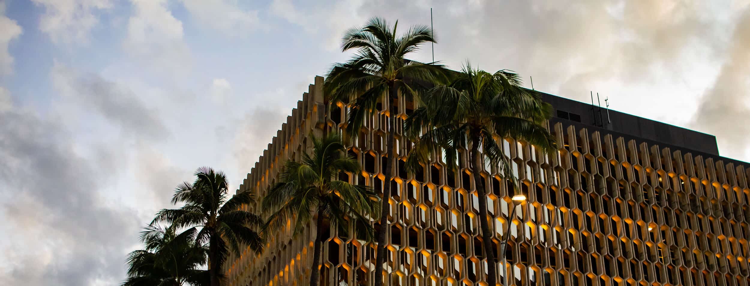 The historic IBM Building facade set against a sunset sky and surrounding palm trees.