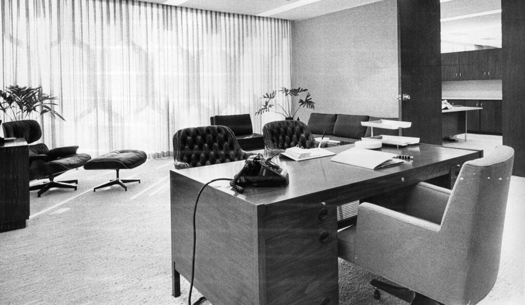 Inside the IBM Building, an empty office with mid-century office decor including an Eames chair and ottoman.