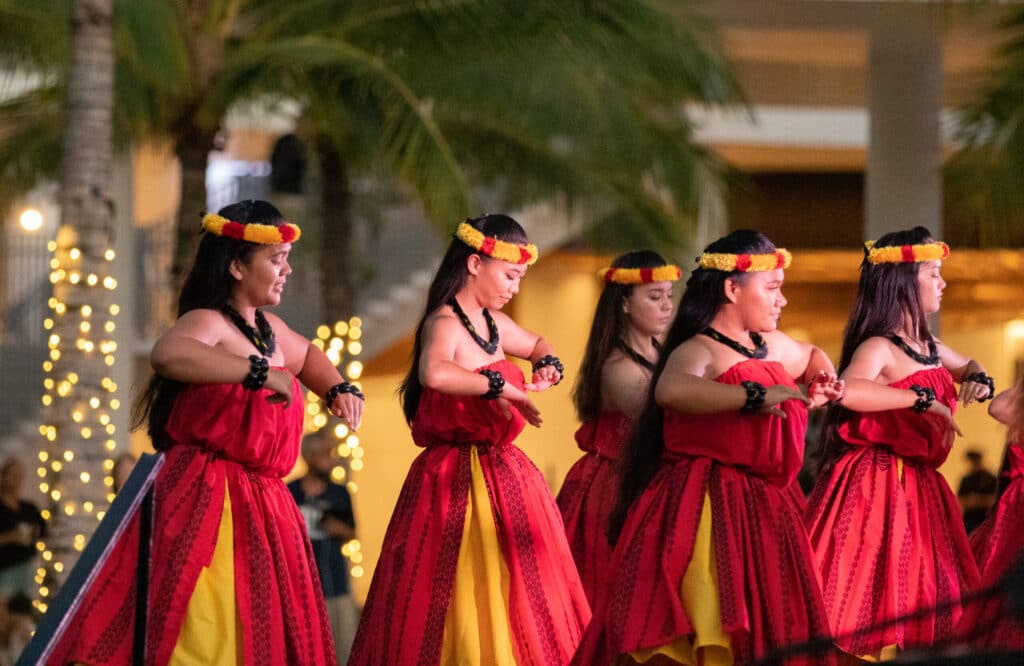 A group of hula dancers with a palm tree in the background