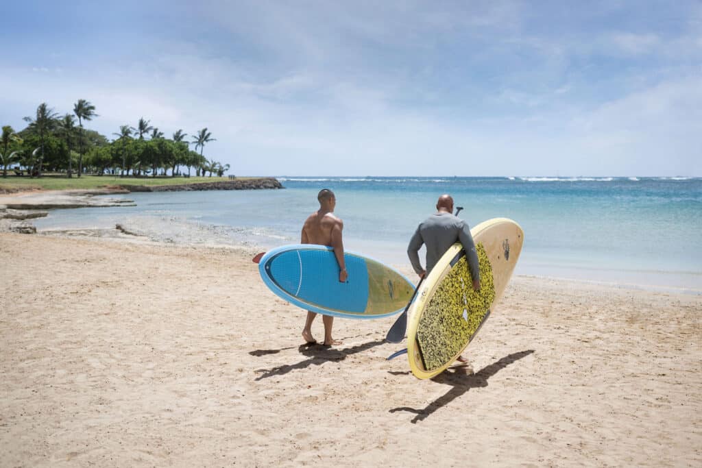 Two men holding their surfboards walking into the ocean