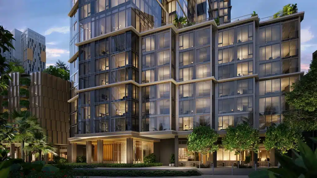 Modern multi-story glass building with illuminated windows at dusk, surrounded by trees and greenery.