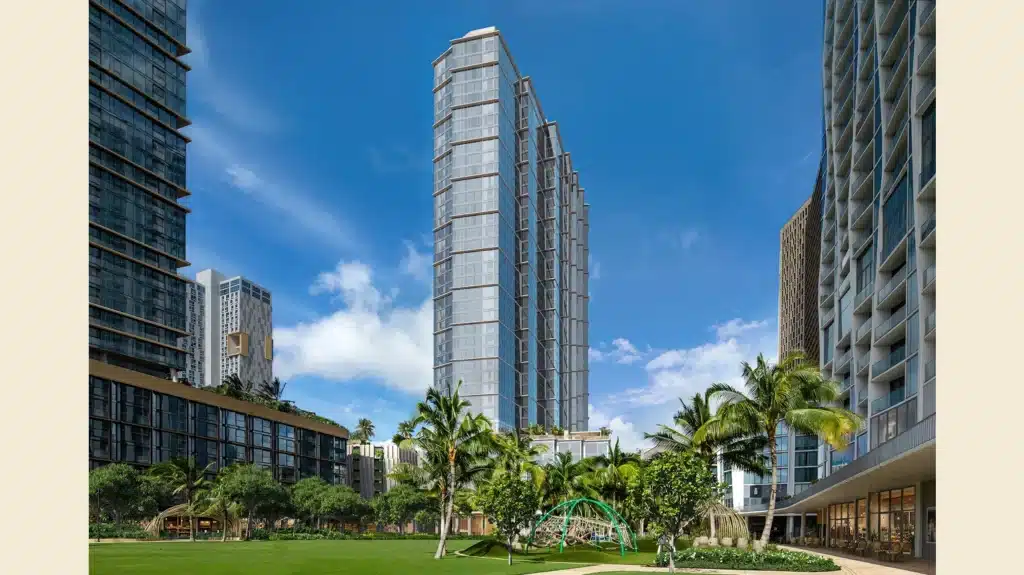 Modern high-rise buildings surround a green lawn with palm trees and a small playground under a bright blue sky.